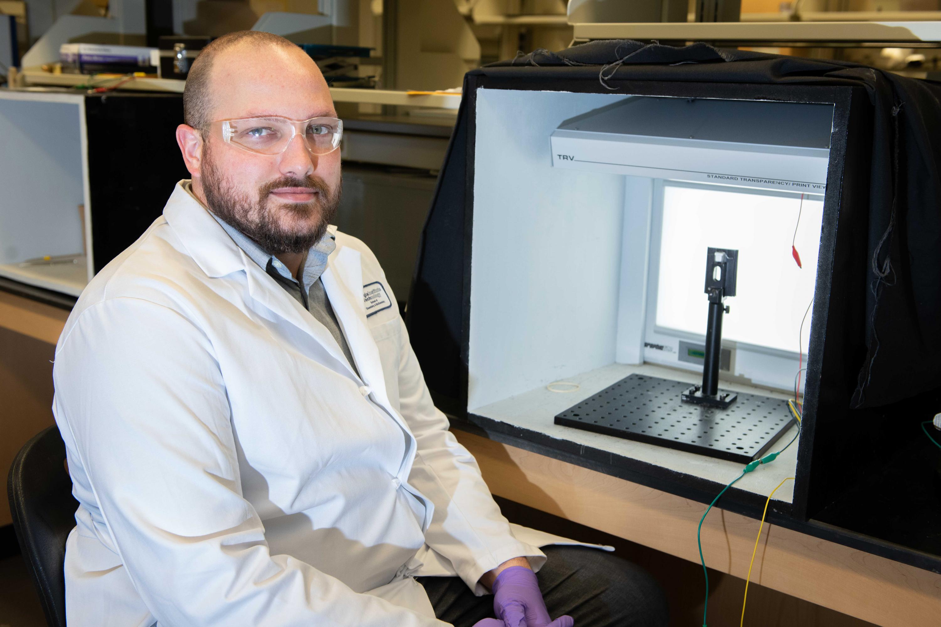 Graduate Research Assistant Dylan Christiansen is shown with a transparent electrochemical cell that allows examination of materials color change upon application of an oxidizing voltage. (Photo: Allison Carter, Georgia Tech) Graduate Research Assistant Dylan Christiansen is shown with a transparent electrochemical cell that allows examination of materials color change upon application of an oxidizing voltage. (Photo: Allison Carter, Georgia Tech)