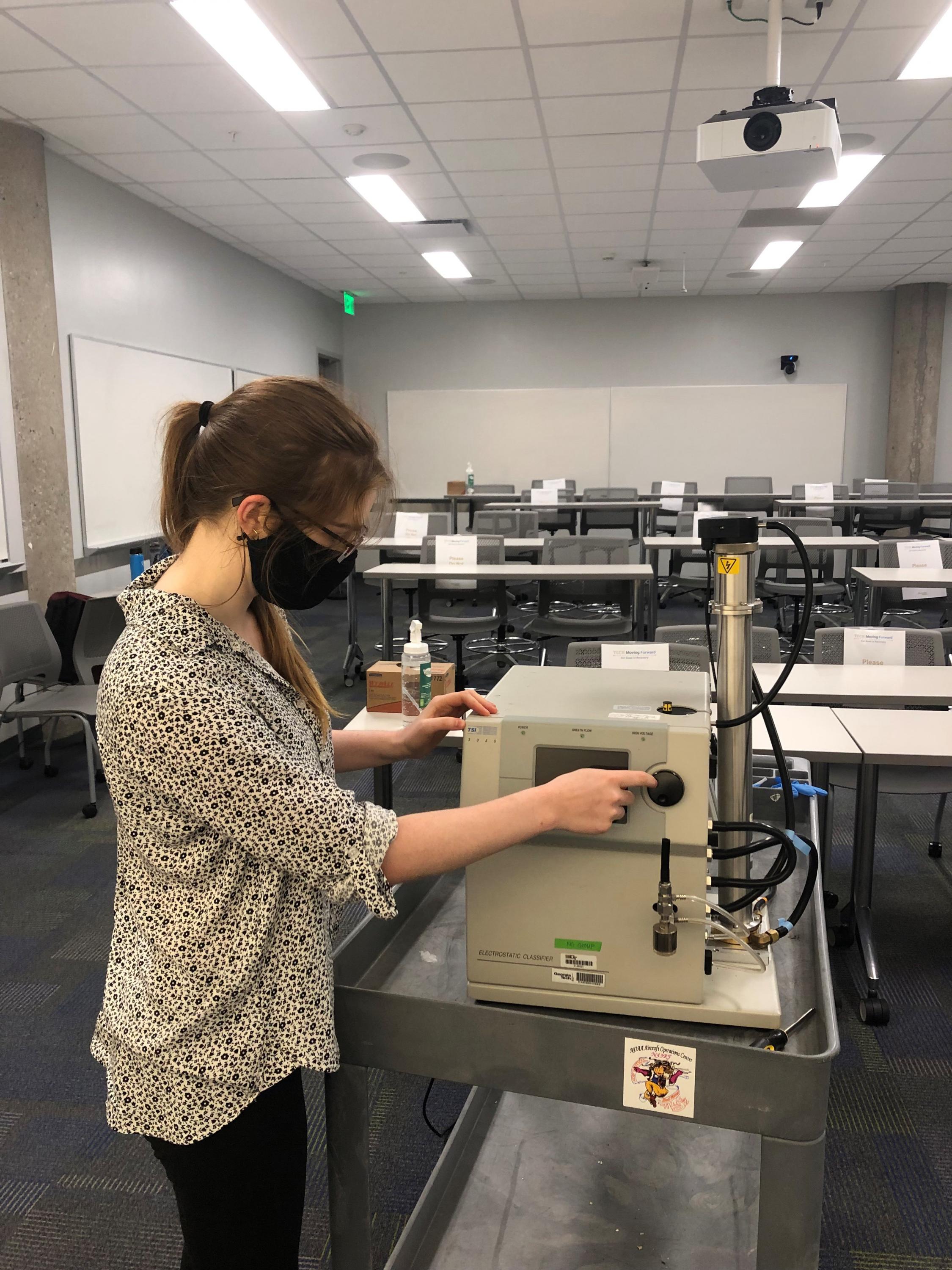 Graduate student Sabrina Westgate measures particle concentration in a classroom. Graduate student Sabrina Westgate measures particle concentration in a classroom.