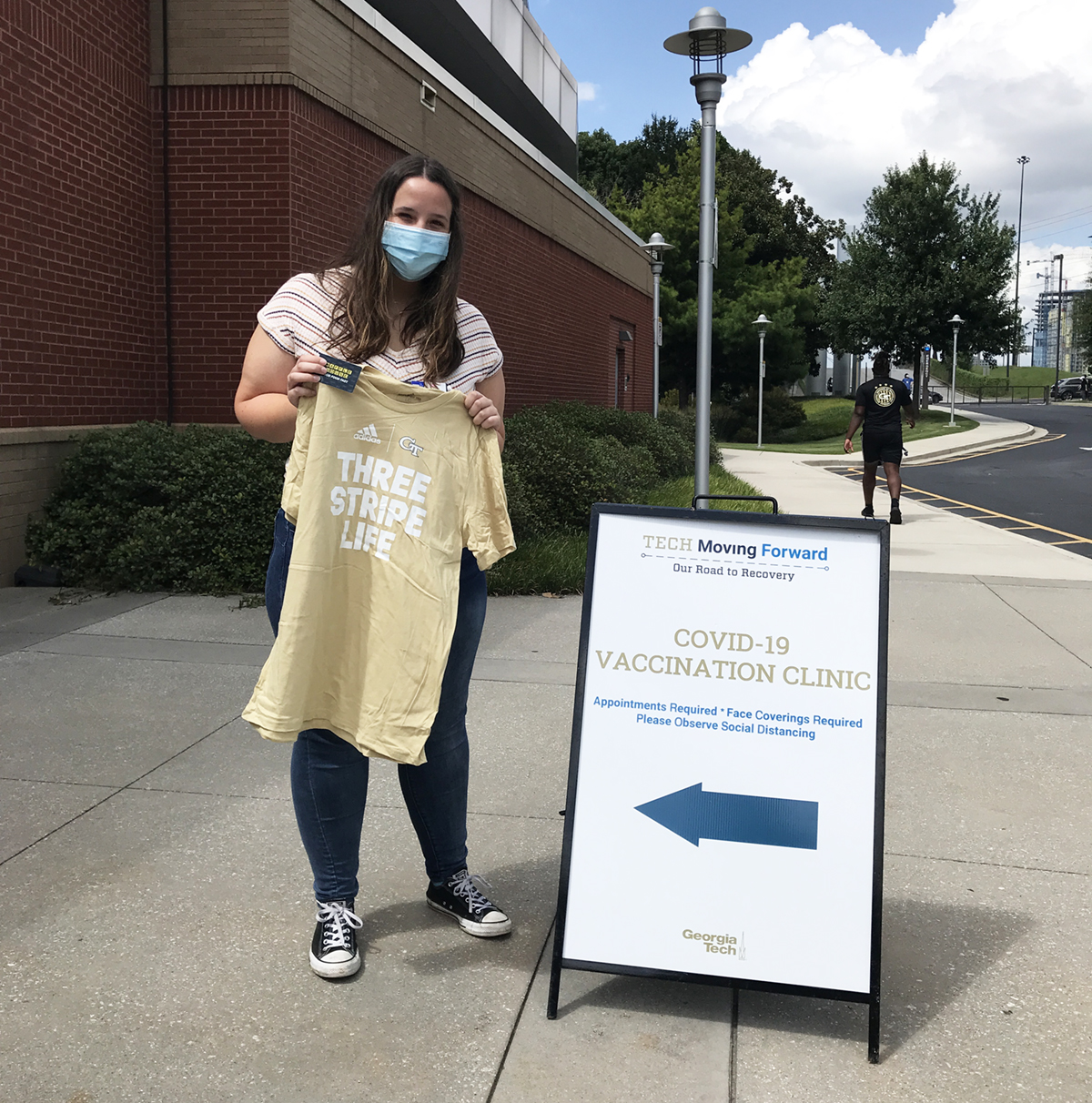 Vaccine clinic volunteer Claire, a third-year student studying biochemistry, holds one of the GT Athletics t-shirts handed out at a recent campus clinic. This month, all students, faculty, and staff who get vaccinated or participate in Covid-19 testing will be eligible for drawings and surprise giveaways of GT Athletics t-shirts and memorabilia, Barnes & Noble at Georgia Tech gift cards, and discount cards for Waffle House, Rusty Taco, and other local businesses. Vaccine clinic volunteer Claire, a third-year student studying biochemistry, holds one of the GT Athletics t-shirts handed out at a recent campus clinic. This month, all students, faculty, and staff who get vaccinated or participate in Covid-19 testing will be eligible for drawings and surprise giveaways of GT Athletics t-shirts and memorabilia, Barnes & Noble at Georgia Tech gift cards, and discount cards for Waffle House, Rusty Taco, and other local businesses.