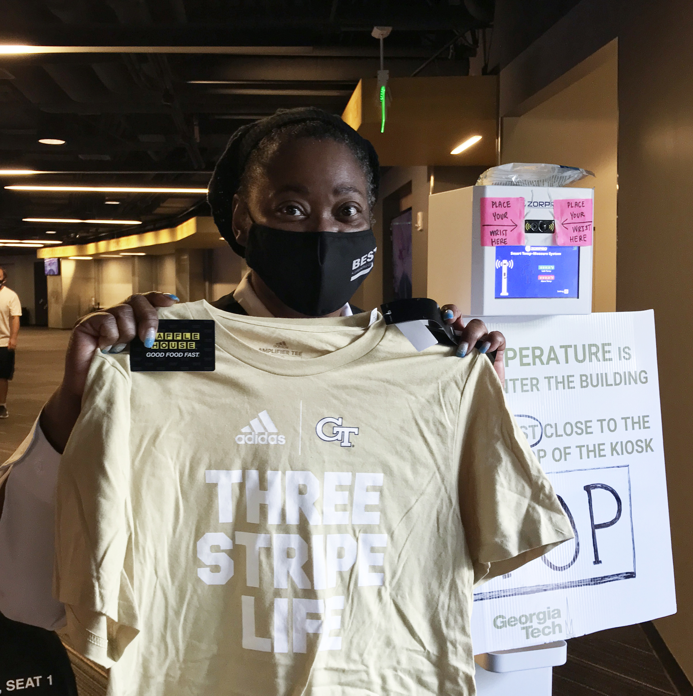 Ms. Keresa, a staff member with Georgia Tech's Covid-19 campus vaccine clinic, holds one of the GT Athletics t-shirts and Waffle House discount cards handed out at a recent campus clinic. Ms. Keresa, a staff member with Georgia Tech's Covid-19 campus vaccine clinic, holds one of the GT Athletics t-shirts and Waffle House discount cards handed out at a recent campus clinic.